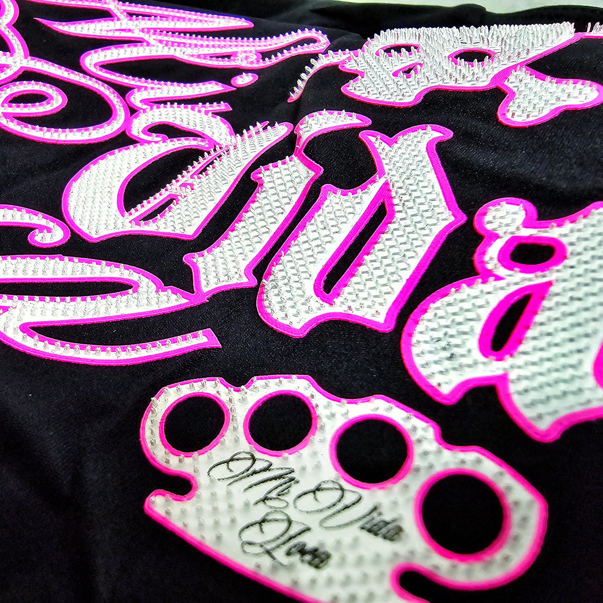 Close-up of the pink and white Babe Skull print with MVL logo on the black top