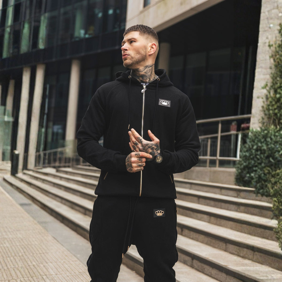 Jogger LFR Tracksuit negro llevado por modelo con la sudadera LFR, torso y parche del logo a la vista