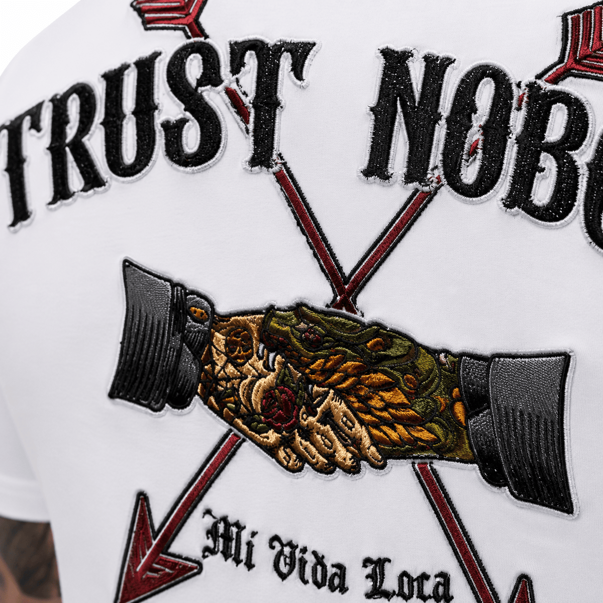 Close-up van het Trust nobody borduurwerk op de rug: handdruk tussen twee pijlen met Mi Vida Loca tekst