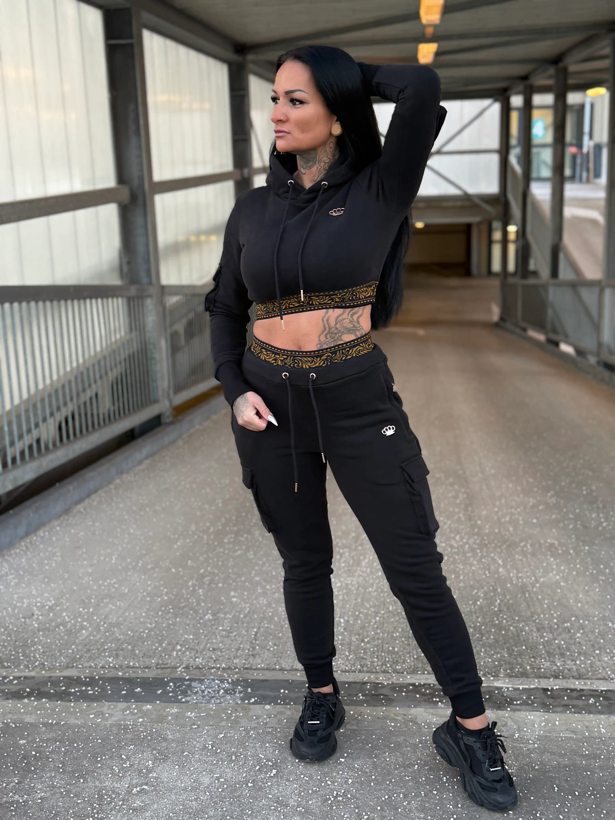 Modelo con el chándal de mujer MVL Meander negro y sudadera corta en una pasarela