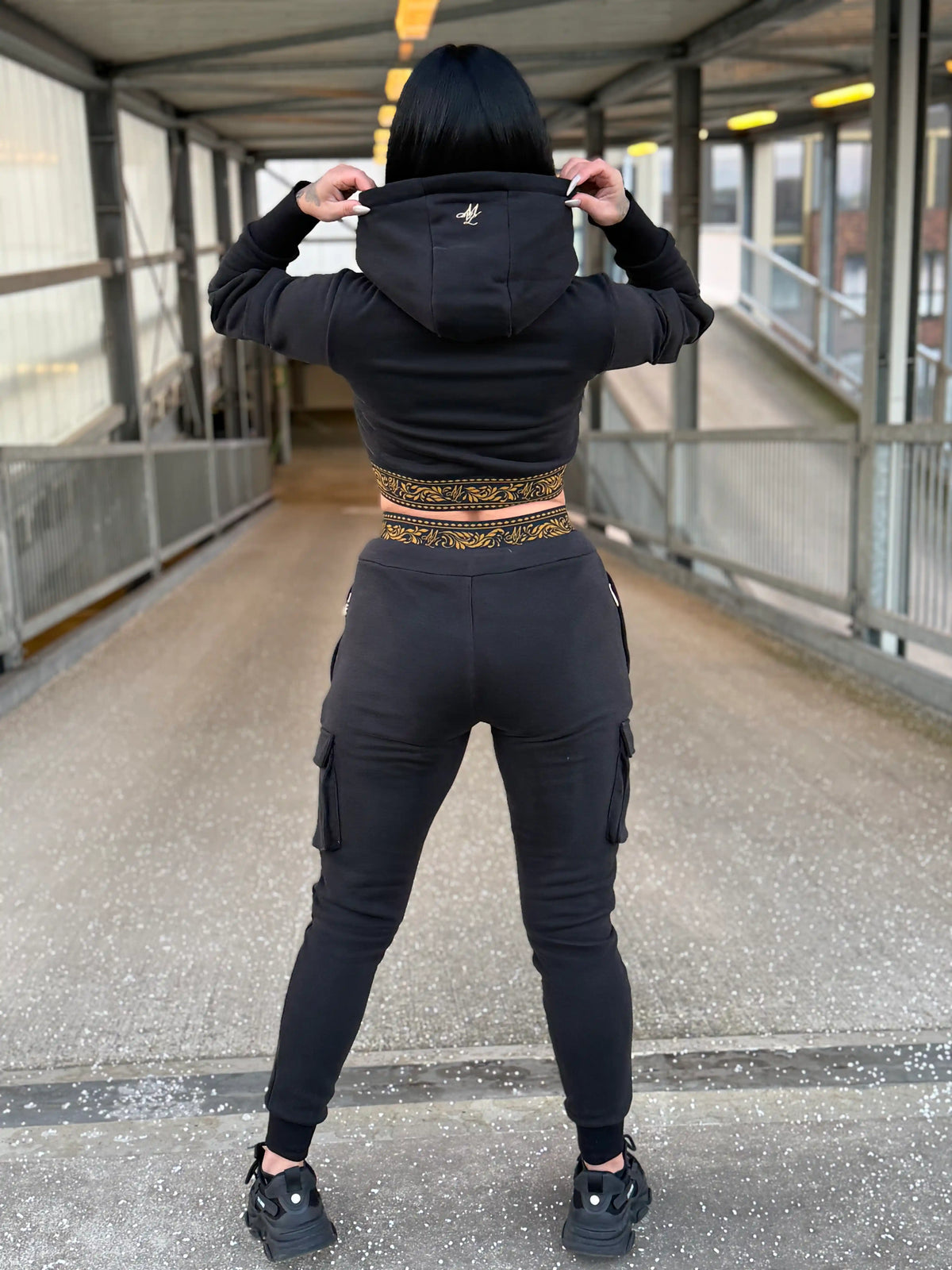 Espalda de la sudadera corta de mujer MVL Meander con la capucha puesta, modelo en una pasarela