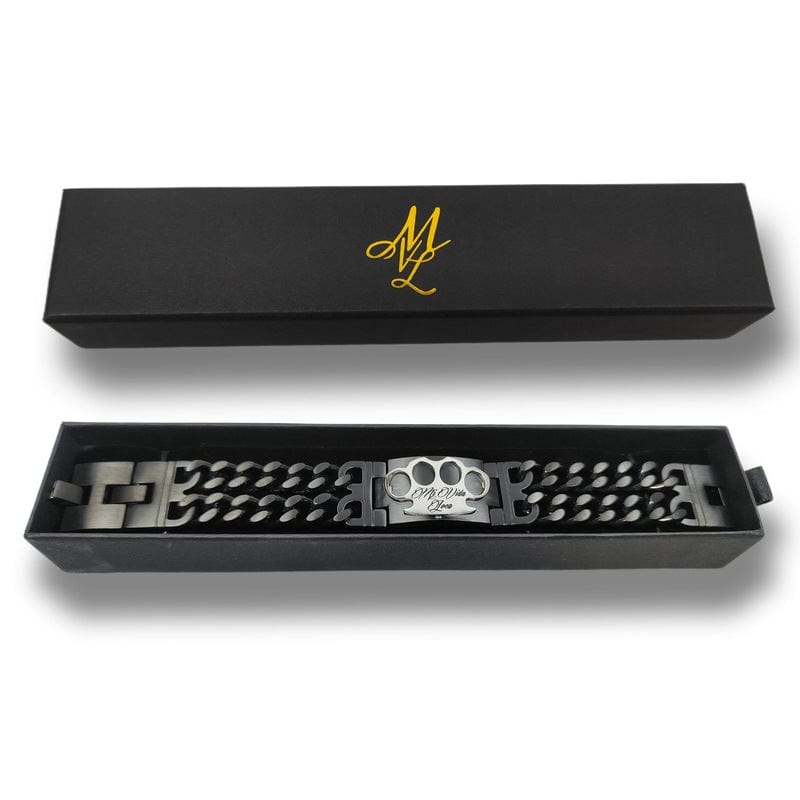 Pulsera Mi Vida Loca negra y plateada con placa del logo MVL plateada, en la caja MVL negra abierta