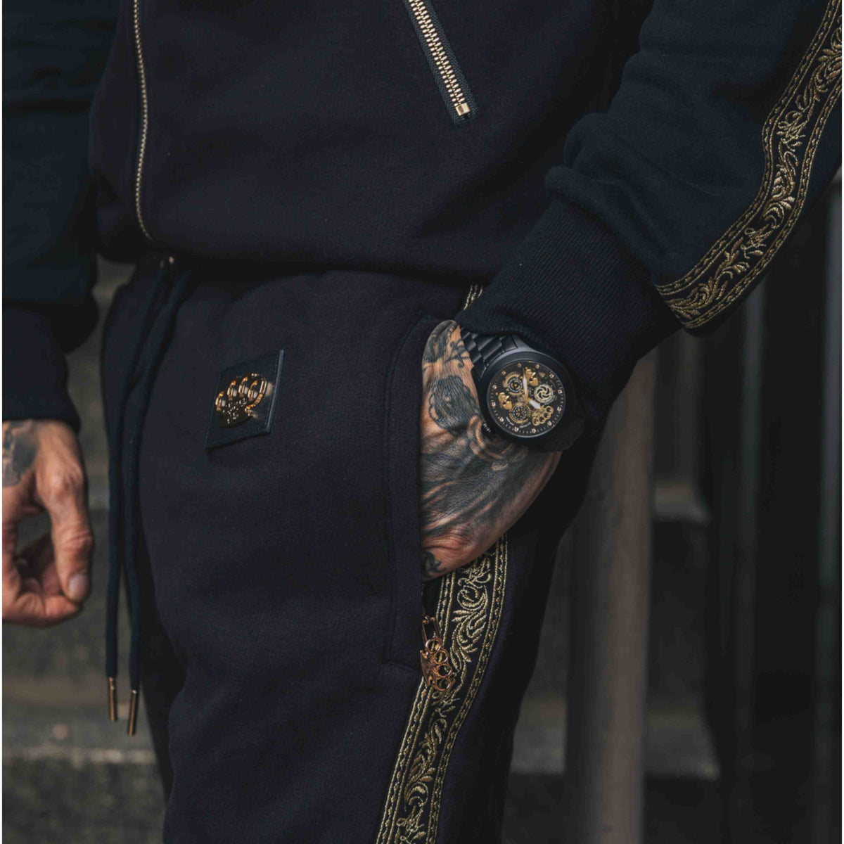 Pantaloni jogger Mi Vida Loca Meander neri con banda ricamata dorata e logo MVL, indossati da modello