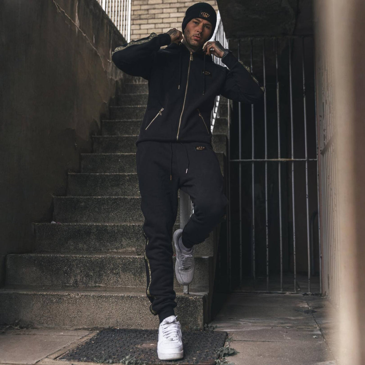 Modello con felpa e pantaloni jogger MVL Meander su una scala esterna, con sneakers bianche