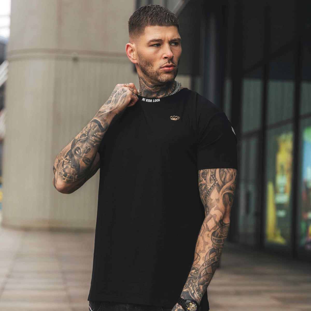 Model w czarnej koszulce MVL FTS, przód z małym logo, na ulicy w mieście