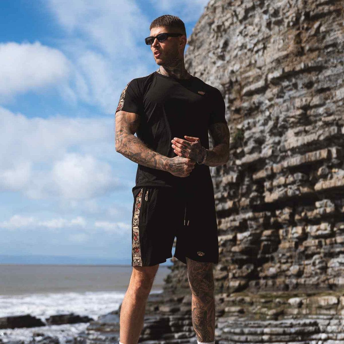 LFR Jogger-Shorts schwarz, getragen von Model mit schwarzem T-Shirt an den Felsen am Meer
