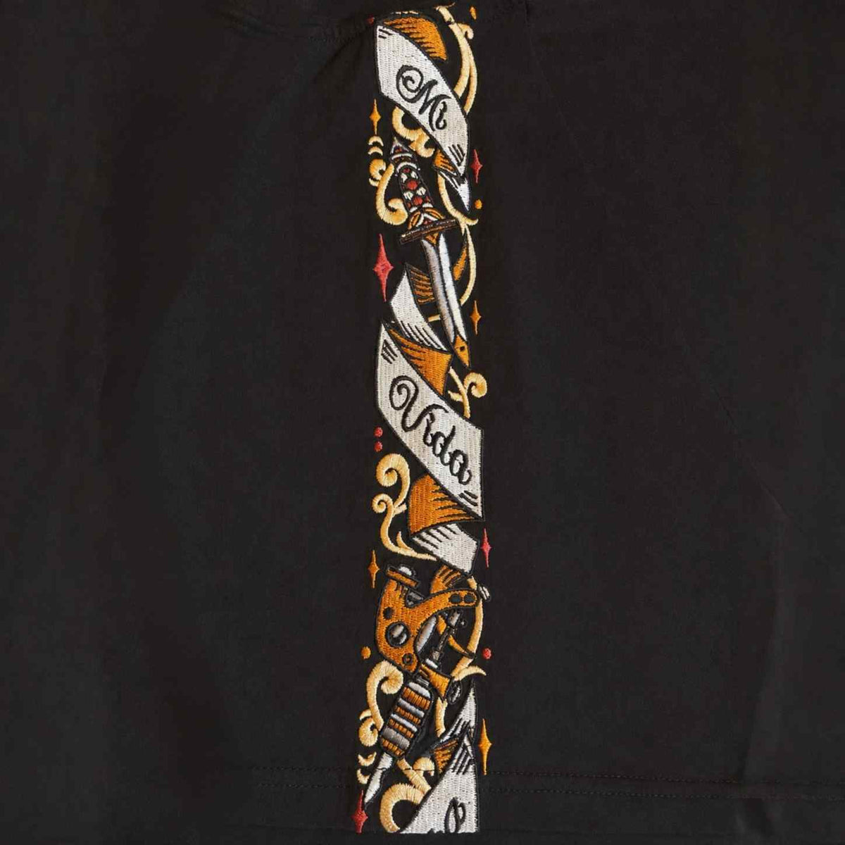 Nahaufnahme des Savage ornate Schulterbands mit Dolch, Rosen und Mi Vida Loca Banner