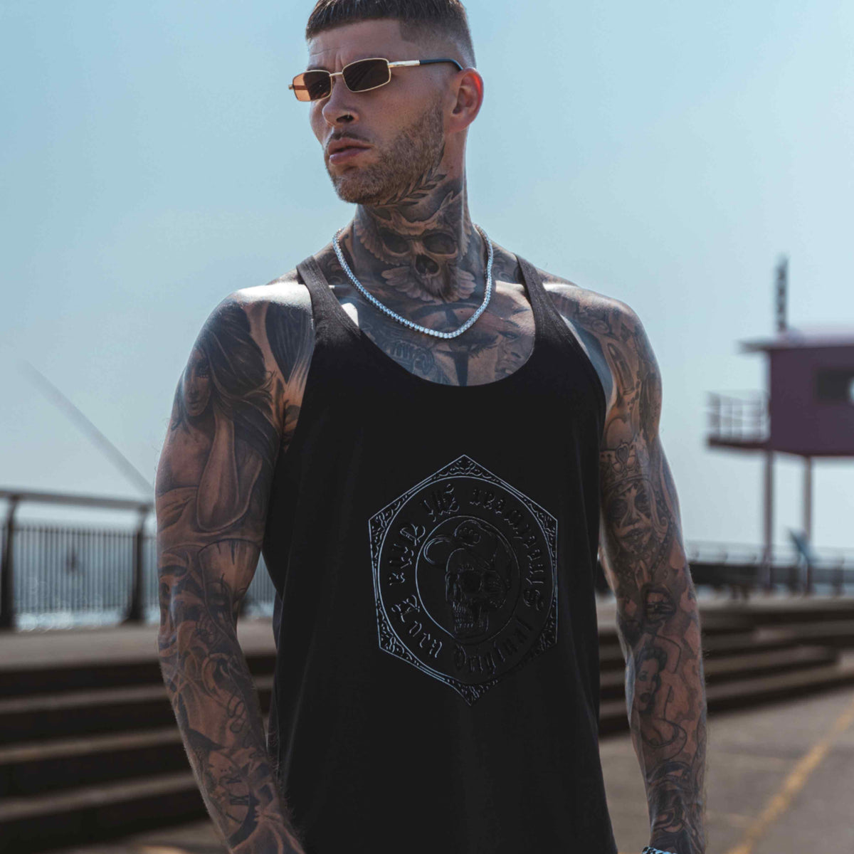 Camiseta de tirantes MVL Original streetwear negra llevada por modelo en un muelle, fotografiada desde abajo