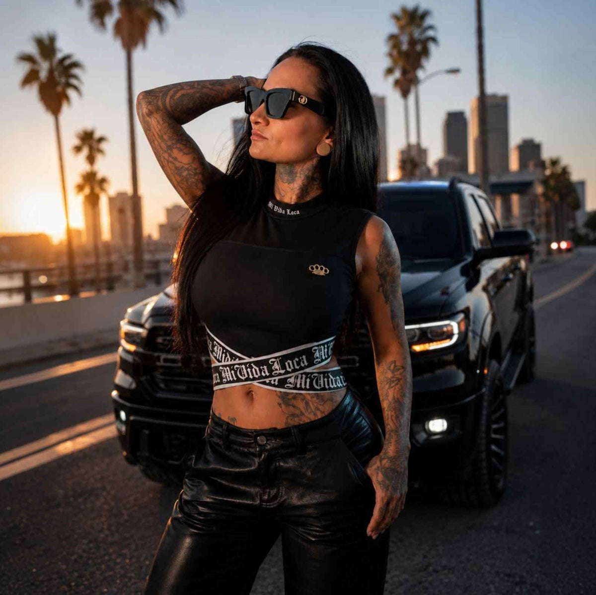 Top da donna Signature nero indossato da modella con occhiali da sole al tramonto tra le palme